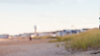 Father carrying son and walking along beach