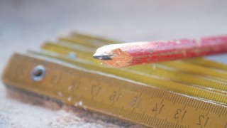 A sharp pencil and wooden ruler on a desk covered in sawdust