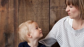 Mother and child sit on a wooden floor with a map