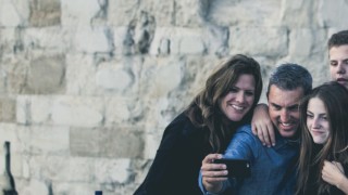 A family taking a group selfie photograph in front of a castle wall